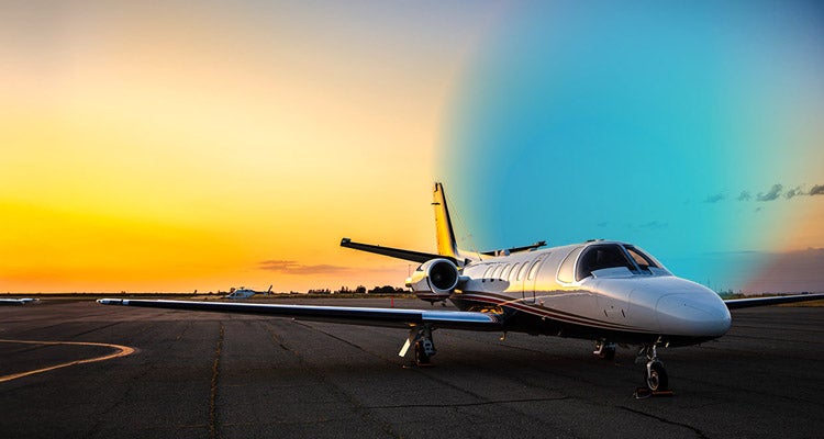 Airplane in a landing strip with the sunset in the background and a blue gradient hovering to the right of it 