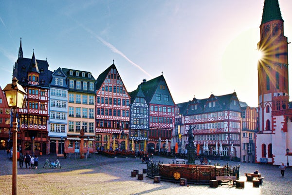 Historic and colorful blue, red, brown and green buildings in a German city with people walking around on a sunny day