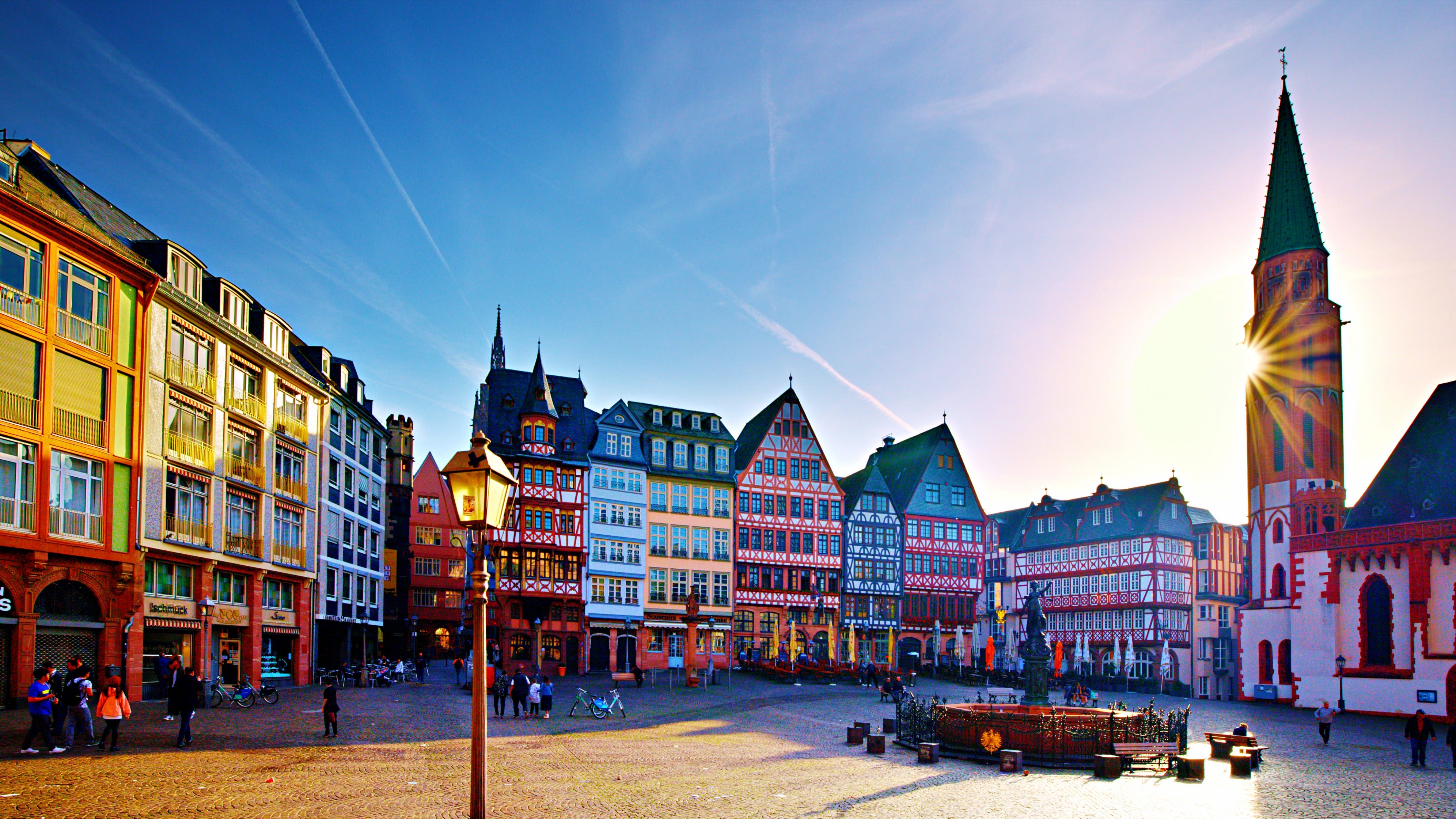 Historic and colorful blue, red, brown and green buildings in a German city with people walking around on a sunny day