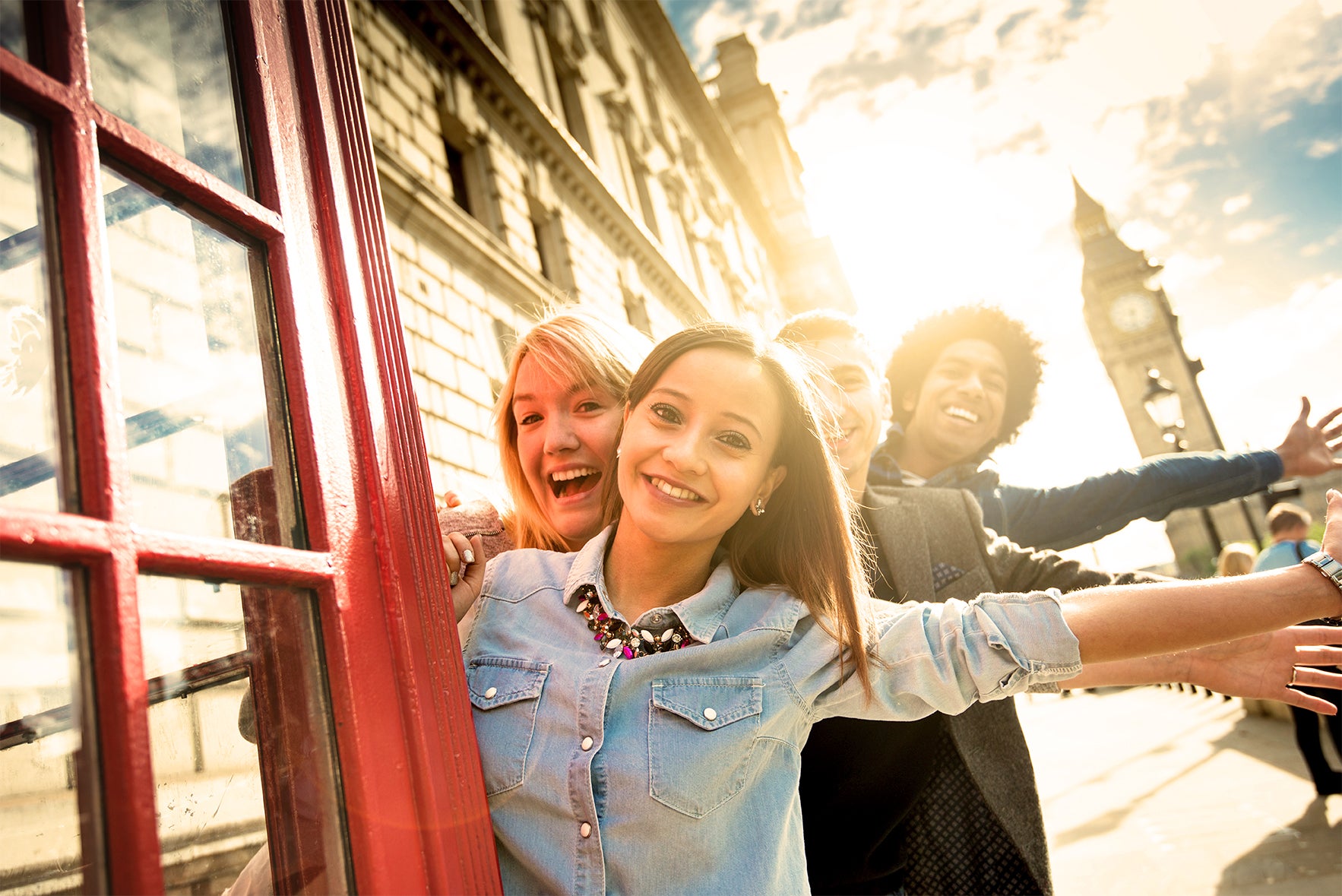 Group of diverse college students smiling and posing outside of a red telephone booth in London with Big Bn in the background 
