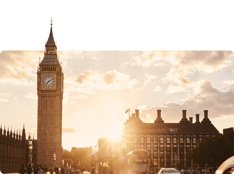 Big Ben in London with people walking in the streets and red double decker buses in the foreground