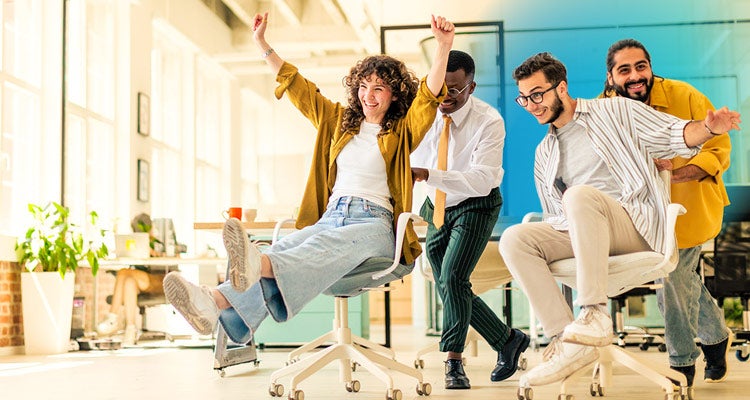 A group of four multiethnic coworkers racing on office chairs and laughing together at work with a blue gradient hovering around them 