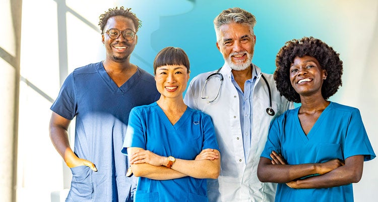 A group of four multiracial medical professionals smiling and wearing blue scrubs with blurred background and blue gradient hovering over them 