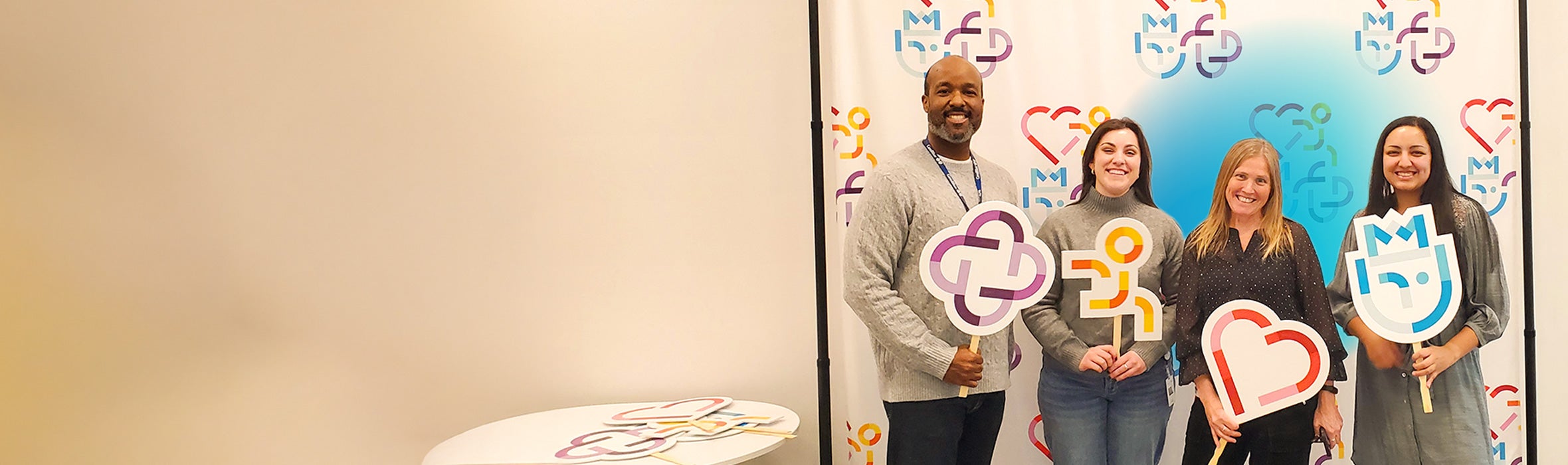 A group of four multiethnic employees at work holding colorful signs representing core values with a blue gradient hovering around them 