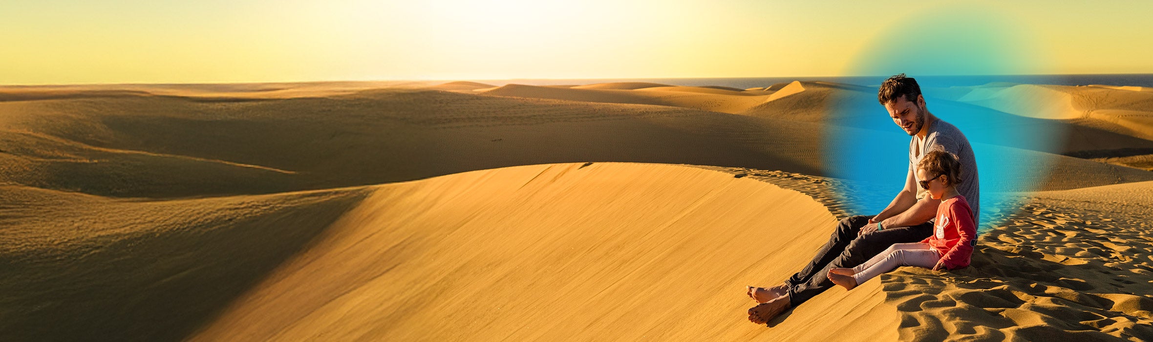 Father and young daughter sitting in a sanded area and a blue gradient hovering around them 