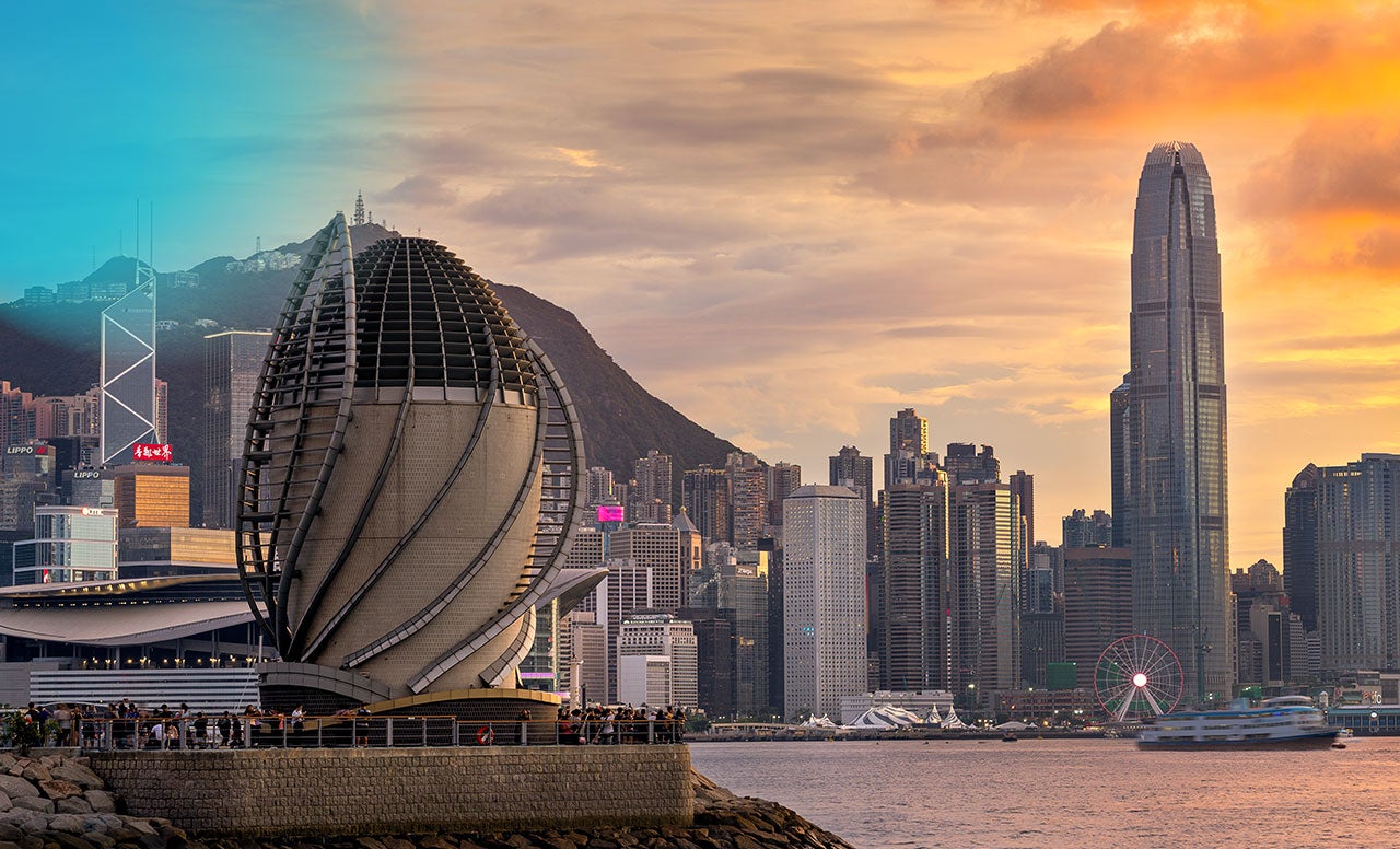 Modern city skyline with unique highrise buildings with water and boats in the foreground and sunset sky 