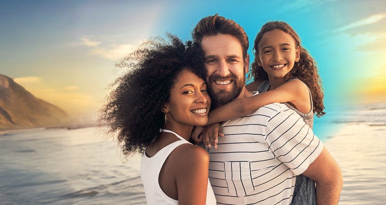 Young African American woman smiling with her Caucasian  husband and their daughter on a beautiful beach 
