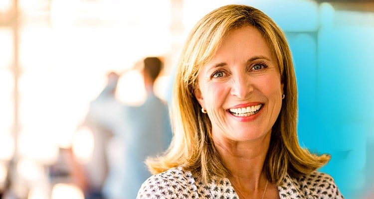 Smiling middle aged Caucasian woman with a blurred background and a blue gradient hovering over her 