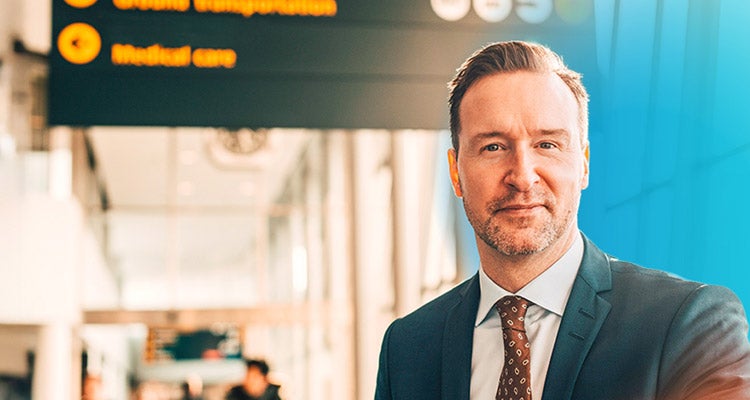 Caucasian businessman in an airport terminal slightly smiling with a blue gradient hovering around him 