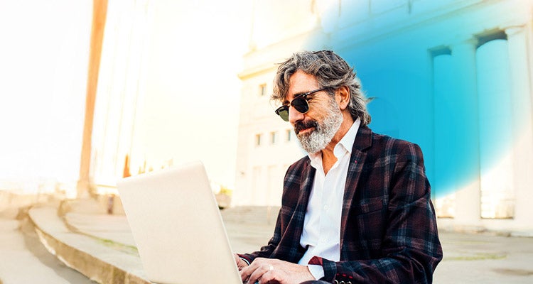 Older businessman sitting outside working on his laptop and blue circled gradient hovering around him