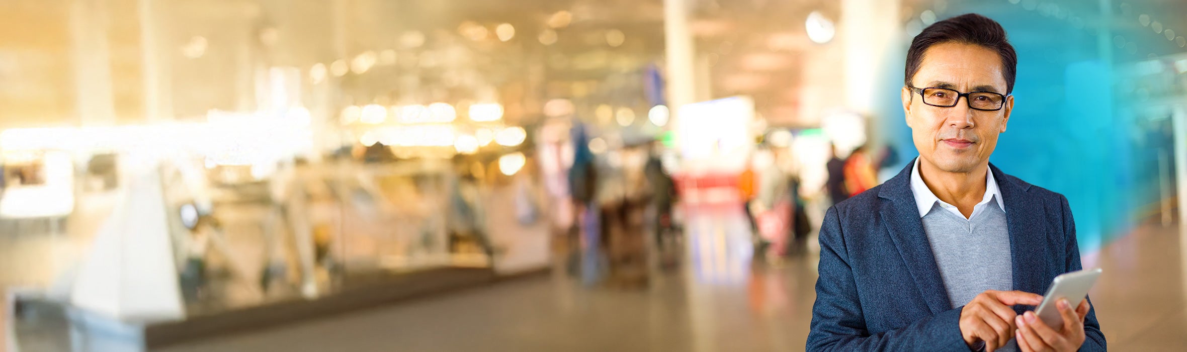 Asian businessman holding a smartphone in airport with blue circled gradient hovering around him
