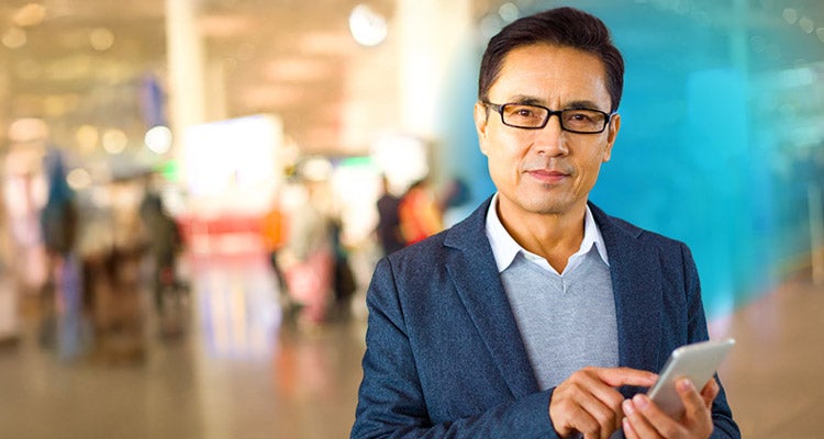 Asian businessman holding a smartphone in airport with blue circled gradient hovering around him
