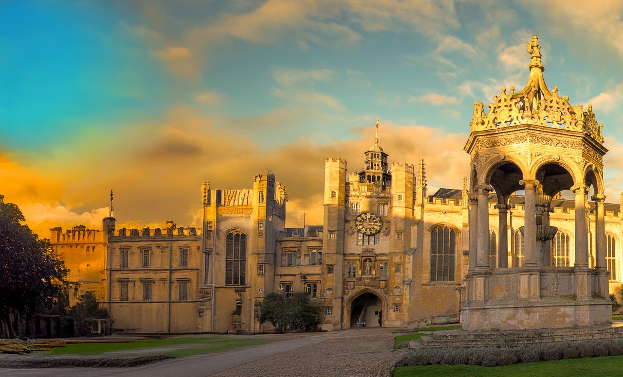 Exterior of the entrance of a European castle with intricate towers and windows lit up by a golden sunset. 