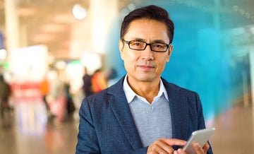 Asian businessman holding a smartphone in airport with blue circled gradient hovering around him