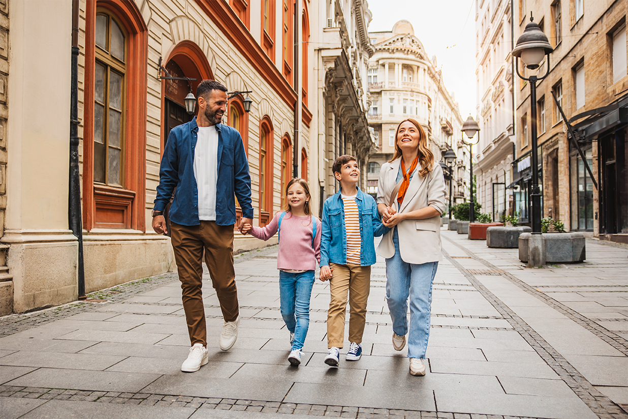 A family of four with two young children and parents walking down a European looking street 