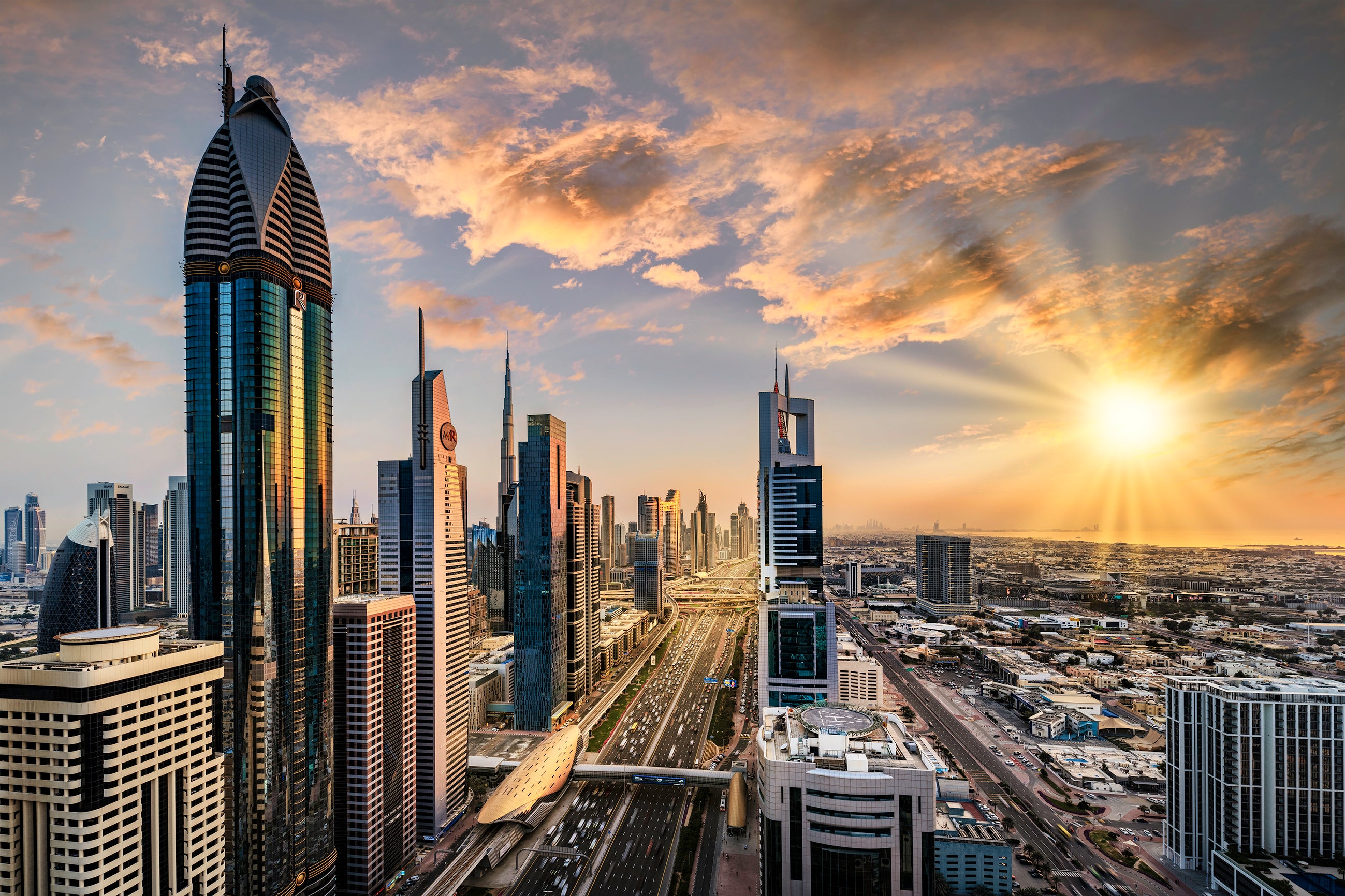 Dubai city skyline buildings in the center with the sunset beaming behind the buildings