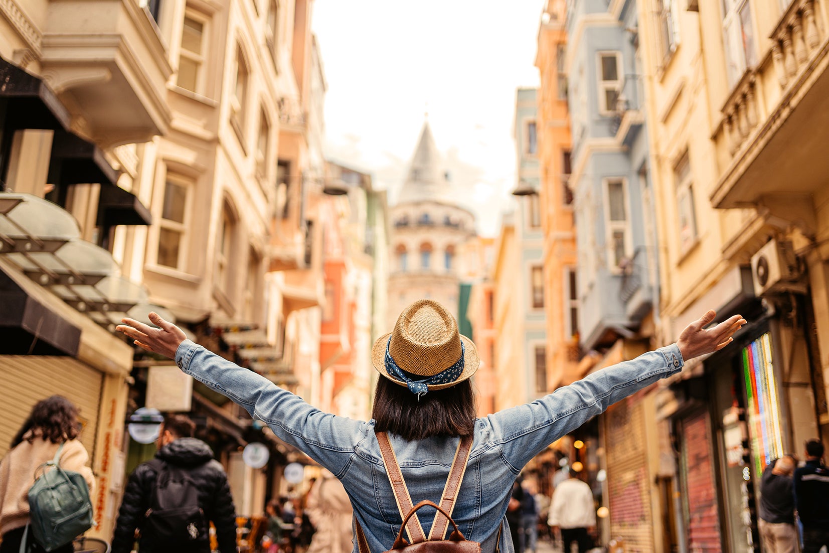 Woman turned around with her hands up outside on a city street during the day wearing a jacket and a hat